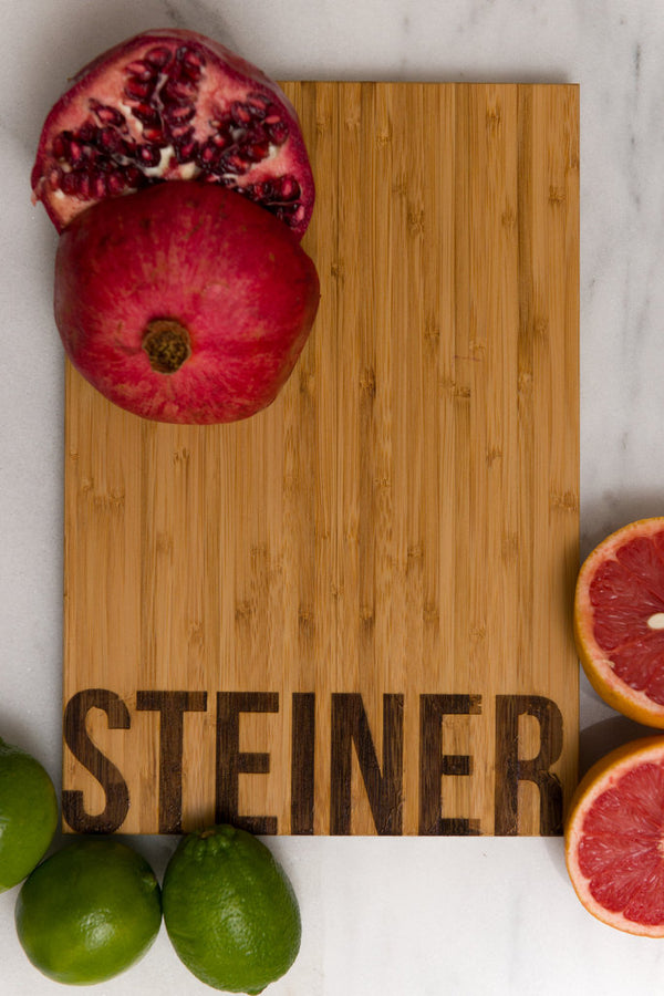 Family Name Personalized Bamboo Cutting Board with fruit surrounding it